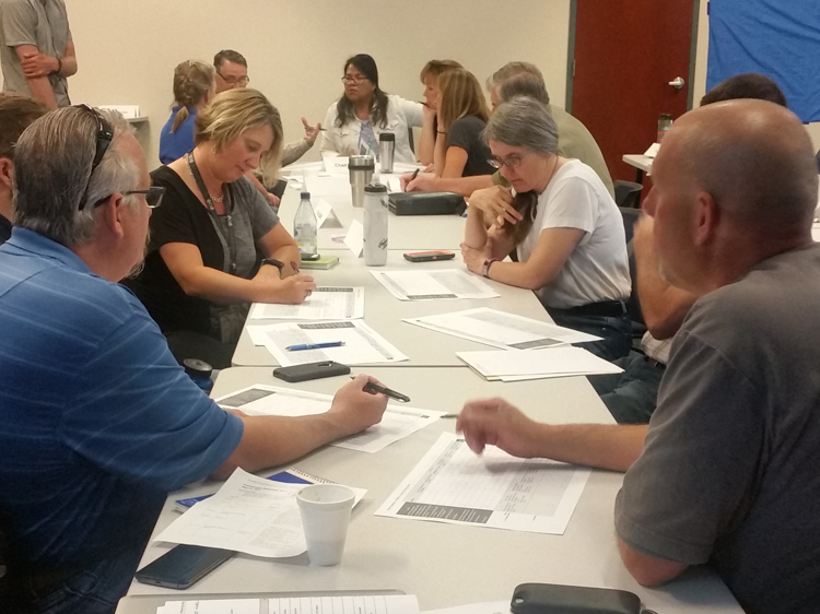 Partners from private, local, state, and federal organizations gather around tables discussing habitat priorities for their region. 